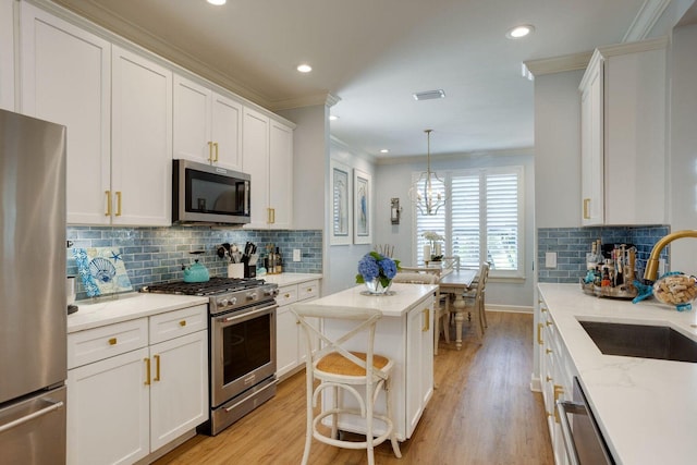 kitchen with pendant lighting, sink, stainless steel appliances, white cabinets, and light stone counters