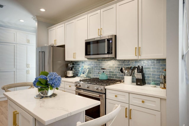 kitchen with white cabinets, a kitchen breakfast bar, light stone counters, and stainless steel appliances