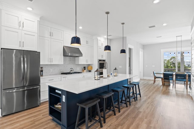 kitchen featuring appliances with stainless steel finishes, pendant lighting, white cabinetry, and an island with sink