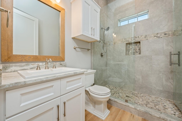 bathroom featuring toilet, a shower with door, vanity, and hardwood / wood-style flooring