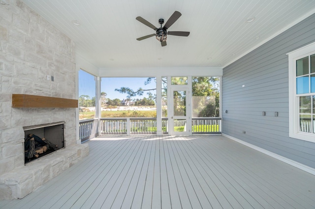 deck featuring an outdoor stone fireplace and ceiling fan