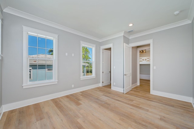 empty room with crown molding and light hardwood / wood-style floors