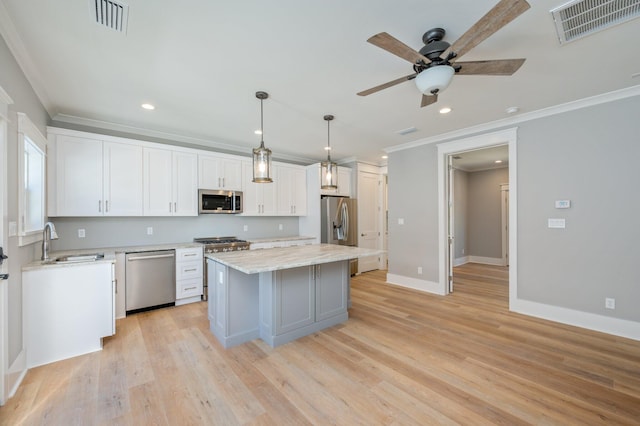 kitchen with stainless steel appliances, light hardwood / wood-style flooring, a center island, white cabinetry, and hanging light fixtures