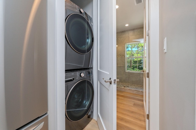 laundry area featuring hardwood / wood-style floors and stacked washer and dryer