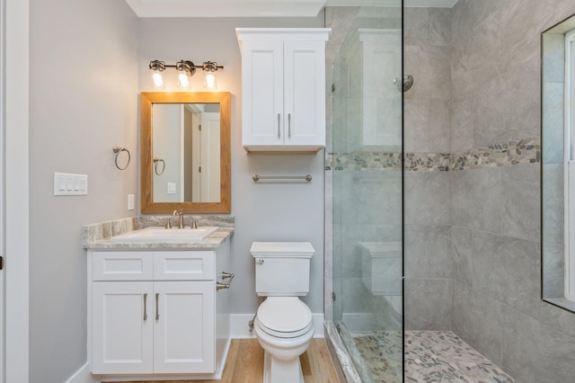 bathroom with hardwood / wood-style floors, vanity, toilet, and a tile shower