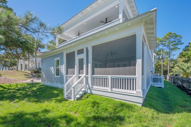 rear view of house featuring a sunroom, ceiling fan, and a yard