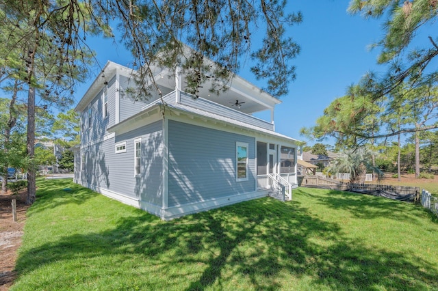 view of property exterior featuring a sunroom, ceiling fan, and a yard