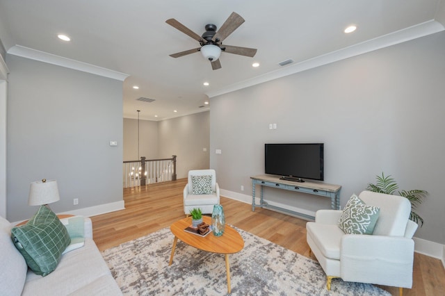 living room with hardwood / wood-style flooring, ceiling fan, and crown molding