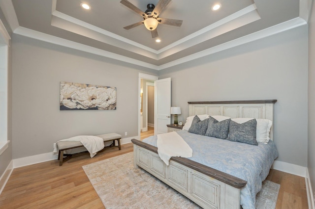 bedroom with light wood-type flooring, a tray ceiling, and ceiling fan