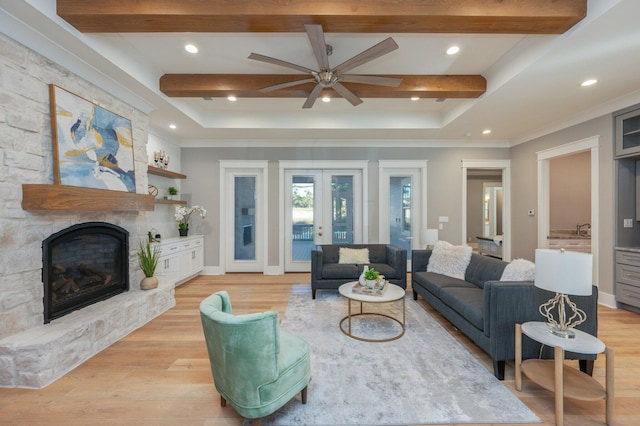 living room featuring beam ceiling, a stone fireplace, french doors, and light hardwood / wood-style flooring