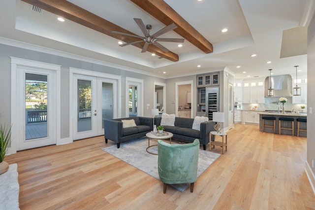 living room with ceiling fan, beam ceiling, french doors, and light hardwood / wood-style flooring