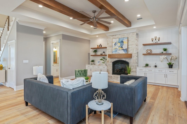 living room with crown molding, light hardwood / wood-style flooring, ceiling fan, a fireplace, and beam ceiling