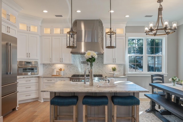 kitchen featuring white cabinets, wall chimney exhaust hood, and stainless steel appliances