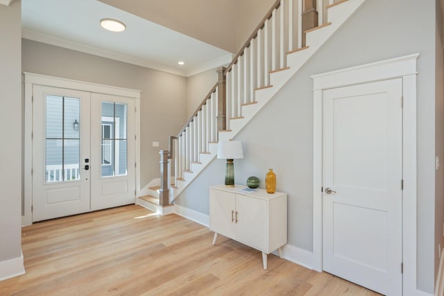 foyer with crown molding, french doors, and light hardwood / wood-style floors