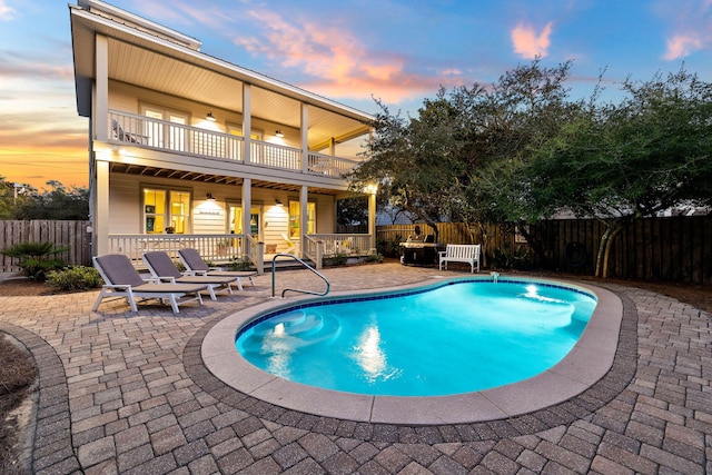 pool at dusk featuring a patio