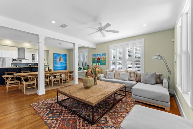 living room featuring ornate columns, ceiling fan, and hardwood / wood-style floors