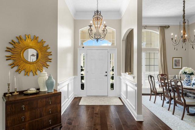 foyer entrance featuring ornamental molding, an inviting chandelier, dark hardwood / wood-style floors, and a textured ceiling