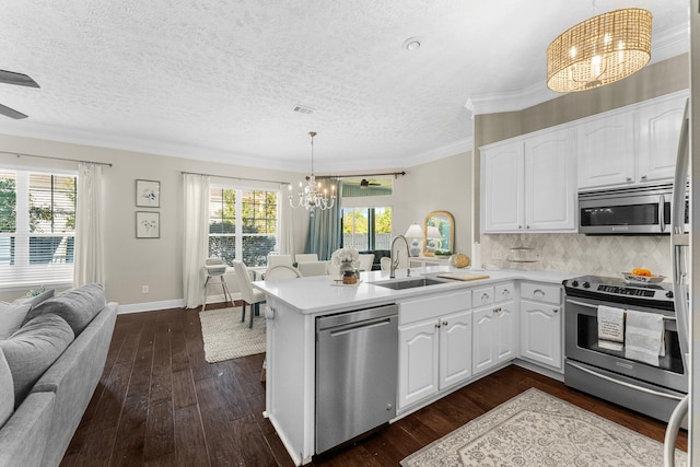 kitchen featuring appliances with stainless steel finishes, kitchen peninsula, white cabinets, and decorative light fixtures