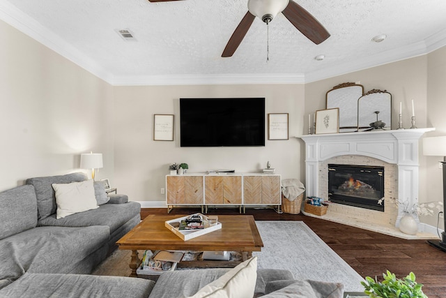 living room with dark wood-type flooring, ceiling fan, a textured ceiling, and ornamental molding