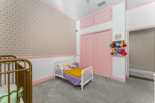 bedroom featuring crown molding, a crib, light carpet, and a closet