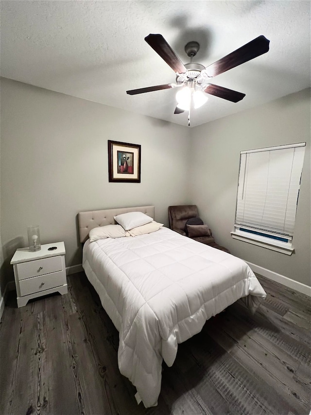 bedroom with a textured ceiling, dark wood-type flooring, and ceiling fan