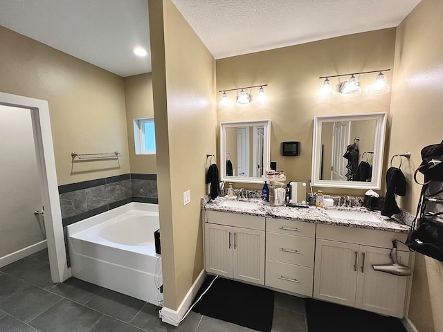 bathroom with vanity, a textured ceiling, a tub, and tile patterned floors