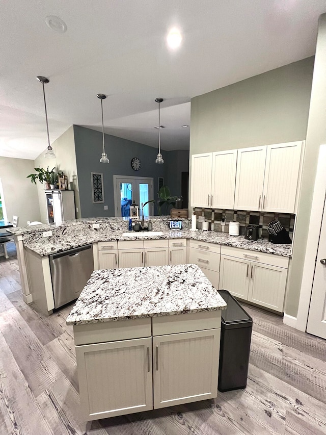 kitchen featuring sink, light wood-type flooring, dishwasher, vaulted ceiling, and decorative light fixtures