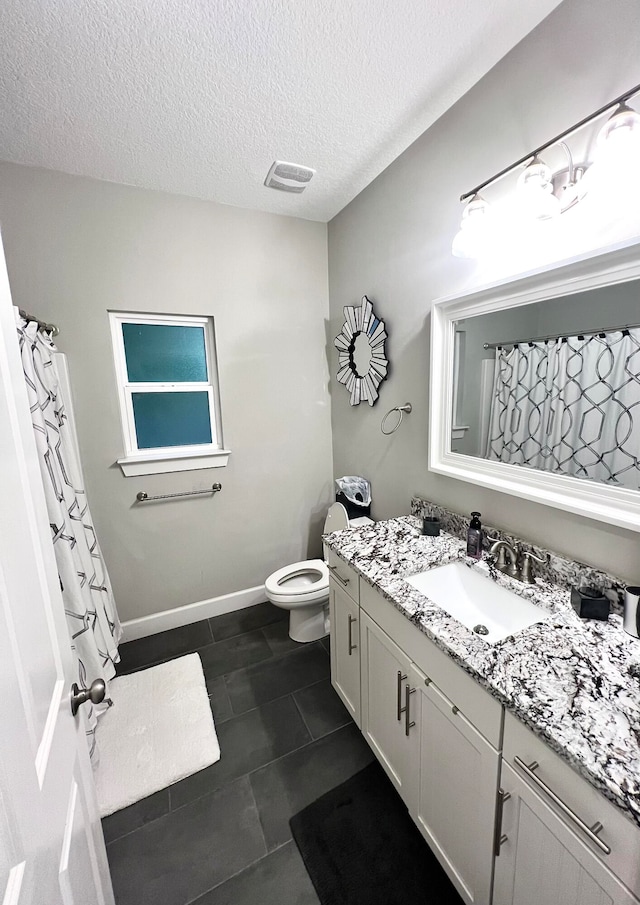 bathroom with vanity, a textured ceiling, toilet, and tile patterned floors