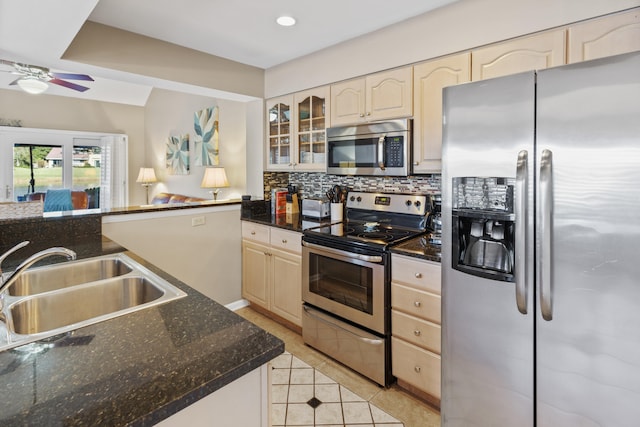 kitchen featuring decorative backsplash, ceiling fan, dark stone counters, sink, and stainless steel appliances