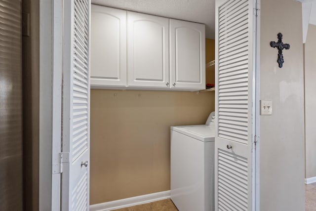 clothes washing area with washer / dryer, a textured ceiling, cabinets, and light tile patterned floors