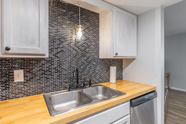 kitchen featuring decorative backsplash, wood-type flooring, dishwasher, pendant lighting, and sink