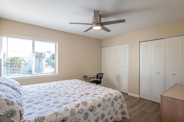 bedroom with ceiling fan, wood-type flooring, and two closets