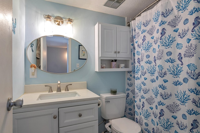 bathroom with vanity, toilet, a textured ceiling, and curtained shower