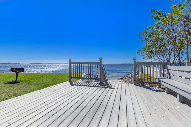 wooden terrace featuring a water view and a lawn