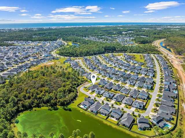 aerial view with golf course view, a wooded view, a residential view, and a water view