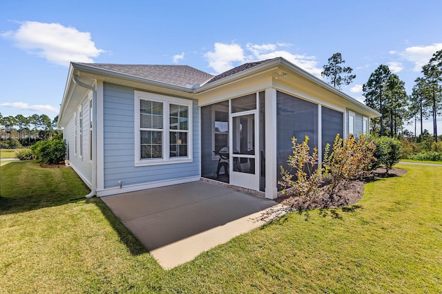back of property featuring a shingled roof, a patio area, a lawn, and a sunroom