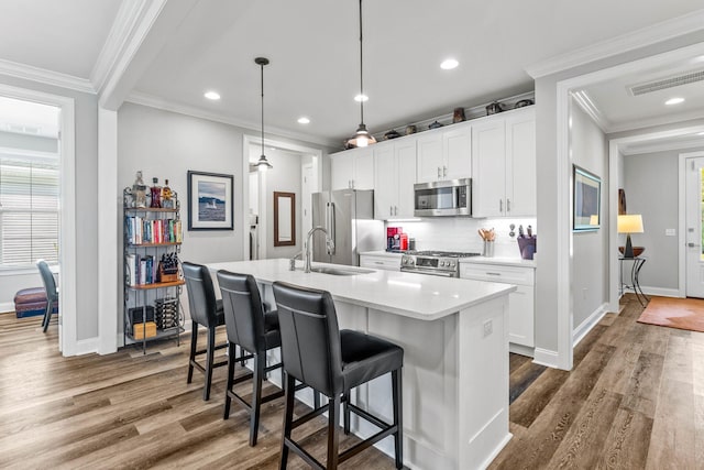 kitchen with white cabinets, dark hardwood / wood-style flooring, an island with sink, pendant lighting, and stainless steel appliances