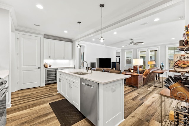 kitchen featuring stainless steel appliances, a sink, light wood-type flooring, beverage cooler, and ornamental molding