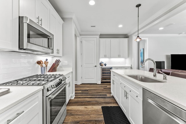 kitchen featuring appliances with stainless steel finishes, dark hardwood / wood-style flooring, hanging light fixtures, white cabinetry, and beverage cooler