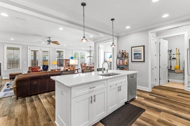 kitchen featuring stainless steel dishwasher, crown molding, a sink, dark wood-style flooring, and recessed lighting