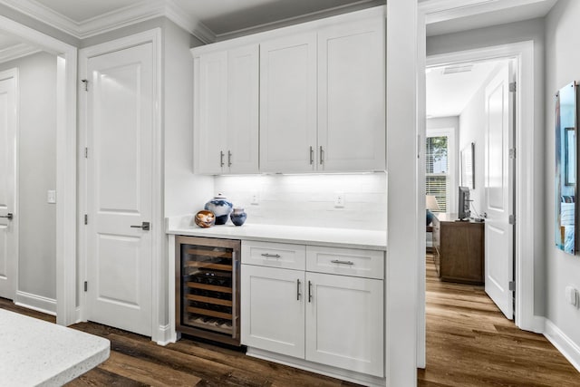bar with a dry bar, dark wood finished floors, baseboards, ornamental molding, and wine cooler
