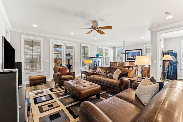 living room with a wealth of natural light, ornamental molding, hardwood / wood-style floors, and ceiling fan