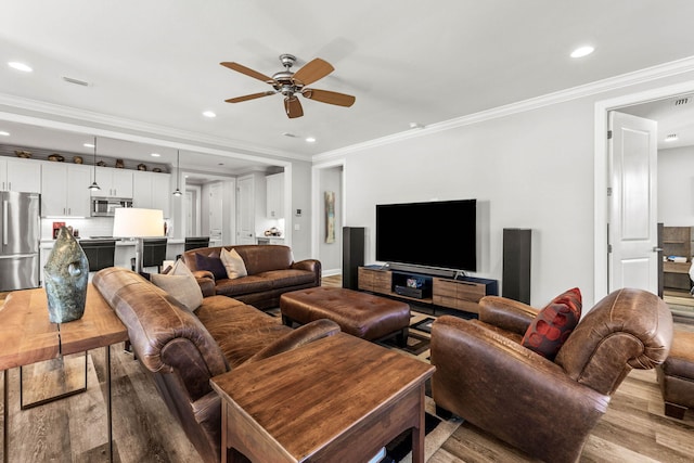 living room with ceiling fan, ornamental molding, and light wood-type flooring