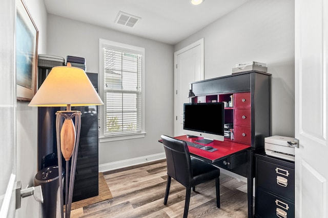 office area with baseboards, wood finished floors, visible vents, and plenty of natural light