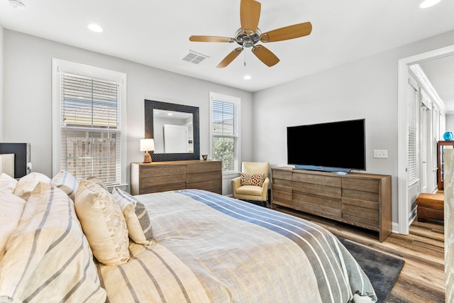 bedroom with ceiling fan, wood-type flooring, and multiple windows