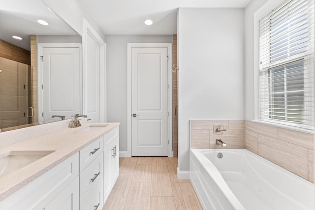 bathroom with a bath, plenty of natural light, double vanity, and a sink