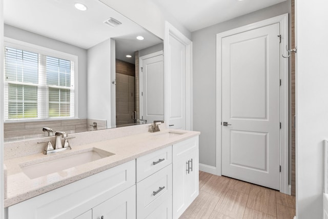 full bathroom featuring recessed lighting, double vanity, a shower stall, and a sink