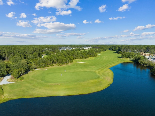 drone / aerial view featuring view of golf course, a view of trees, and a water view