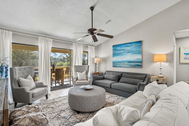 living room with ceiling fan, a textured ceiling, lofted ceiling, and light wood-type flooring