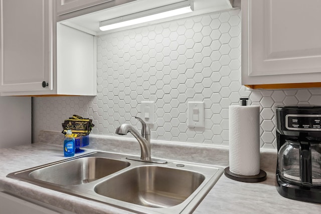 interior details featuring sink, white cabinetry, and decorative backsplash